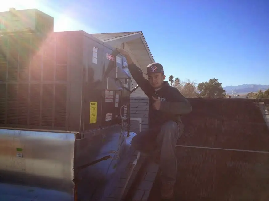 HVAC technician performing Air Duct Cleaning on a rooftop unit in Silsbee